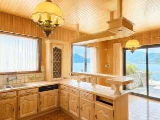 Experience breathtaking lake views from this charming kitchen, featuring warm wood paneling and a cozy breakfast bar.