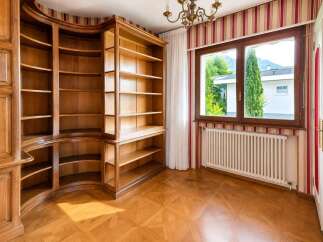 Step into this elegant room featuring a stunning, custom-built wooden bookshelf that curves gracefully around the corner, offering ample storage and a sophisticated aesthetic.