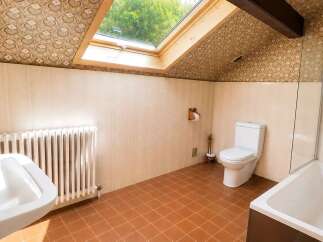 This charming bathroom features a spacious bathtub, a modern sink, and a convenient toilet, all set against a backdrop of tiled walls and a unique patterned ceiling.