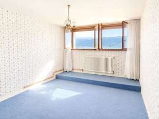 Experience breathtaking lake and mountain views from this charming room, featuring a raised platform carpeted in serene blue.