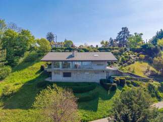 Nestled on a lush green hillside, this modern home offers stunning panoramic views.