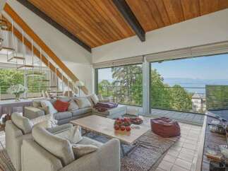 Experience breathtaking lake views from this stunning living room, featuring a modern sectional sofa and a unique floating staircase.
