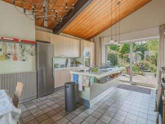Discover this spacious kitchen featuring a large island with a sink, ample cabinet space, and a stainless steel refrigerator.