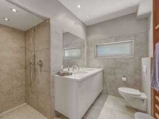 This modern bathroom features a spacious walk-in shower with tiled walls and a sleek showerhead.