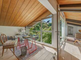 Discover this charming attic office space, bathed in natural light and featuring a sloped wooden ceiling.