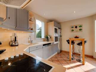 This charming kitchen features light wood cabinetry and a sleek induction stovetop, perfect for culinary enthusiasts.