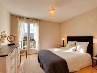 Experience serene living in this charming bedroom, bathed in natural light from a private balcony overlooking a picturesque landscape.