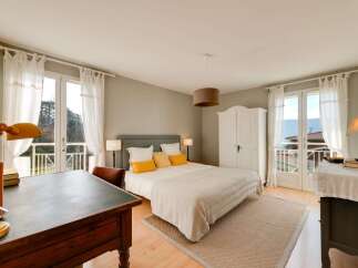 Experience serene living in this charming bedroom, featuring a comfortable bed adorned with plush yellow pillows and a cozy striped blanket.
