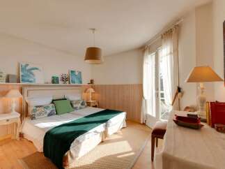 This charming bedroom features two twin beds adorned with tropical-themed pillows and a cozy green throw blanket.