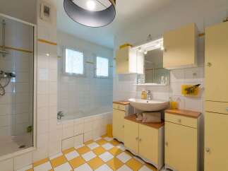 This charming bathroom features a bright and airy design with white tiled walls and a playful yellow and white checkered floor.