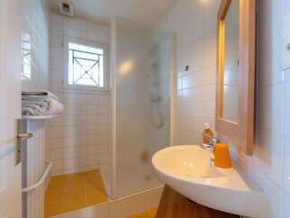 This bright and clean bathroom features a spacious walk-in shower with frosted glass doors, perfect for a refreshing start to your day.