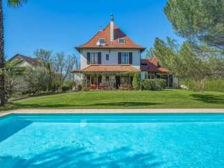 Experience luxury living with this stunning property featuring a beautiful swimming pool and a charming house with a red tile roof.