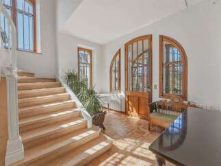 Step into this charming entryway featuring a grand staircase with plush carpeting and an elegant white balustrade.
