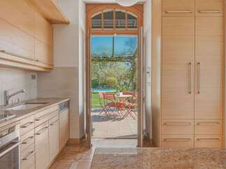 This charming kitchen features light wood cabinetry and a granite countertop, offering ample storage and a sleek, modern aesthetic.