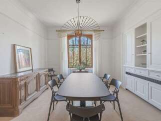 This elegant dining room features a large, dark oval dining table surrounded by modern black chairs, perfect for hosting gatherings.