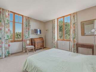 This charming bedroom features two large wooden-framed windows offering picturesque views of the surrounding greenery.