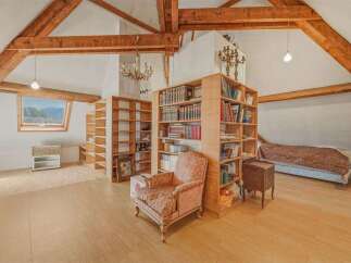 Discover this charming attic bedroom featuring exposed wooden beams and a unique dormer window offering scenic views.