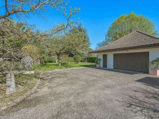 Discover this charming property featuring a spacious driveway leading to a detached garage with two large doors.