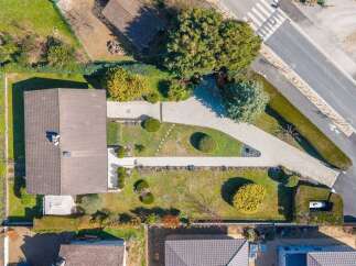 Discover this stunning aerial view of a modern single-family home featuring a spacious driveway and meticulously landscaped gardens.