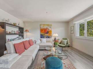 Experience modern living in this beautifully appointed living room, featuring a spacious sectional sofa adorned with coral accent pillows.