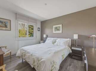 This charming bedroom features a comfortable queen-size bed adorned with floral-patterned linens, complemented by two matching nightstands with lamps.