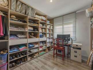 Discover this spacious walk-in closet, meticulously organized with ample shelving for clothing and accessories.