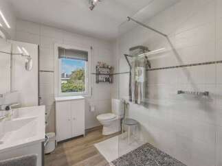 This modern bathroom features a spacious walk-in shower with a glass enclosure and a convenient handheld showerhead.