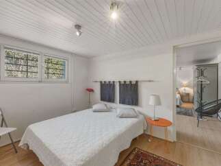 Discover this charming bedroom featuring a comfortable bed with white quilted bedding, complemented by two dark grey decorative curtains hanging above.