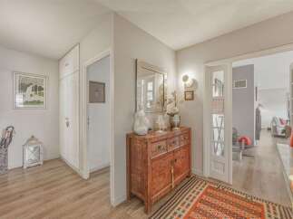 Step into this charming entryway featuring a decorative antique cabinet topped with elegant decor and a large mirror.