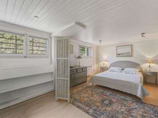 Discover this charming bedroom featuring a comfortable queen-size bed adorned with crisp white linens and plush pillows.