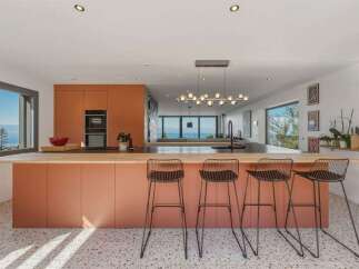 Experience modern living in this stunning kitchen featuring a vibrant terracotta island with ample seating, perfect for entertaining.