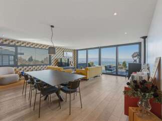 Experience breathtaking lake views from this modern living and dining area, featuring expansive floor-to-ceiling windows that flood the space with natural light.