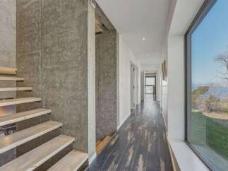Experience modern living in this stunning home featuring a floating staircase with natural wood treads and a sleek concrete accent wall.