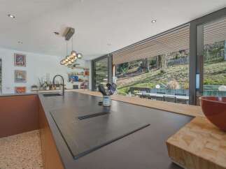 Experience modern living in this stunning kitchen featuring a sleek island with an integrated cooktop and a stylish faucet.