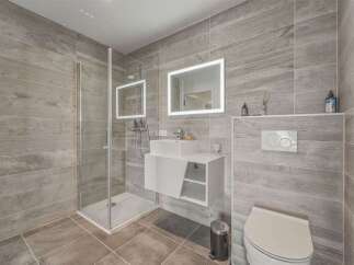This modern bathroom features a sleek walk-in shower with glass enclosure and a floating vanity with integrated sink.