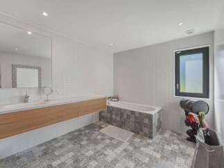 This modern bathroom features a floating wood vanity with a sleek countertop and integrated sink, complemented by a large wall mirror.
