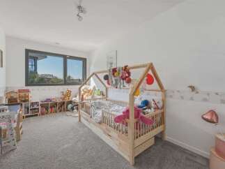 This charming children's bedroom features a whimsical house-shaped bed, perfect for sparking imagination.