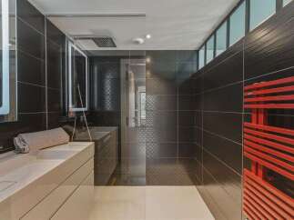Experience modern luxury in this sleek bathroom, featuring a spacious walk-in shower with elegant black tilework and a geometric pattern accent.