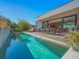Experience modern luxury with this stunning property featuring a sleek infinity pool and expansive wooden deck, perfect for entertaining.