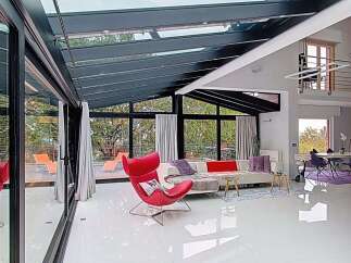 Experience modern living in this stunning sunroom featuring a sleek white sectional sofa and a vibrant red accent chair.