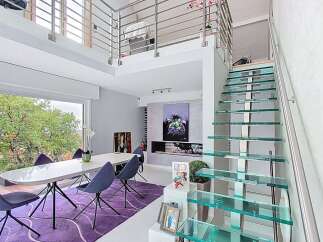 Experience modern luxury in this stunning multi-level home featuring a sleek dining area with a large picture window overlooking lush greenery.