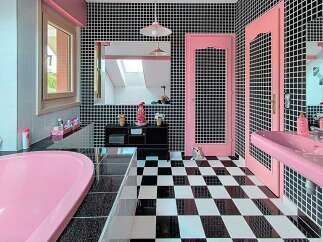 Step into a whimsical bathroom featuring a vibrant pink bathtub and a matching double vanity, all set against a striking black and white checkered floor.