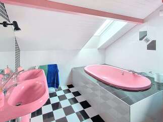 Step into a whimsical bathroom featuring a vibrant pink double sink and a matching pink bathtub, creating a playful and unique aesthetic.
