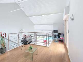 This modern loft space features a sleek metal and glass railing overlooking a pool area, perfect for entertaining.
