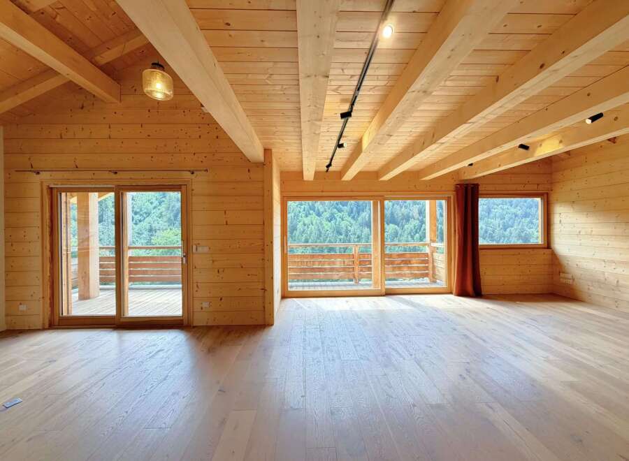 Experience rustic luxury in this stunning wooden interior, featuring a vaulted ceiling with exposed beams and a track lighting system.