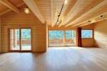 Experience rustic luxury in this stunning wooden interior, featuring a vaulted ceiling with exposed beams and a track lighting system.