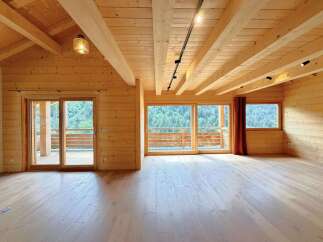 Experience rustic luxury in this stunning wooden interior, featuring a vaulted ceiling with exposed beams and a track lighting system.