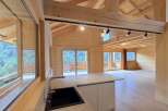Experience modern mountain living in this stunning wooden chalet, featuring an open-concept living space with panoramic windows showcasing breathtaking forest views.