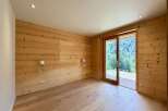 Experience rustic charm and modern comfort in this beautifully appointed room featuring warm, wood-paneled walls and a sleek, light wood floor.