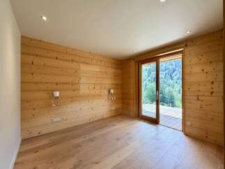 Experience rustic charm and modern comfort in this beautifully appointed room featuring warm, wood-paneled walls and a sleek, light wood floor.